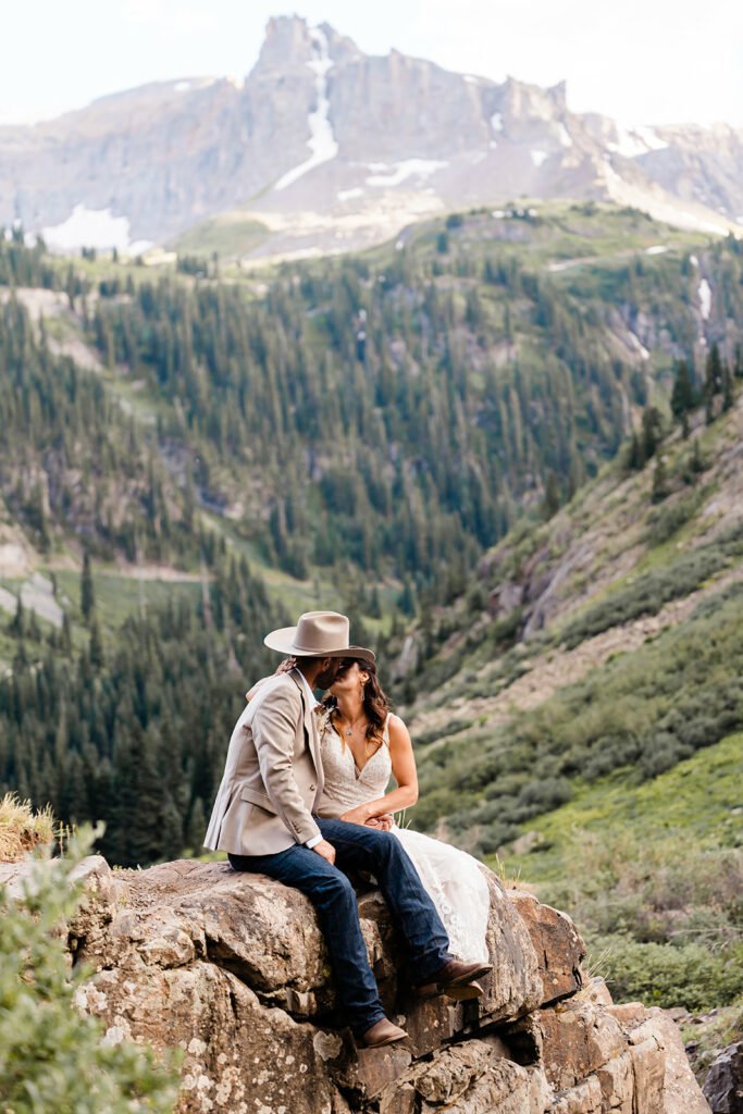 A couple shares a kiss in the mountains on their wedding day. 