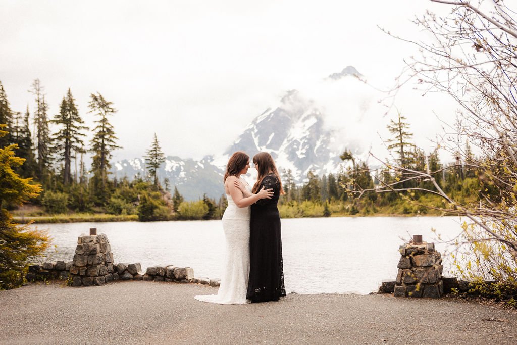 Two brides face each other on a foggy morning in the mountains.