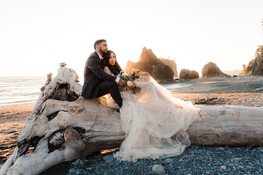 A couple sits together on a tree on the coast line of Olympic National Park.