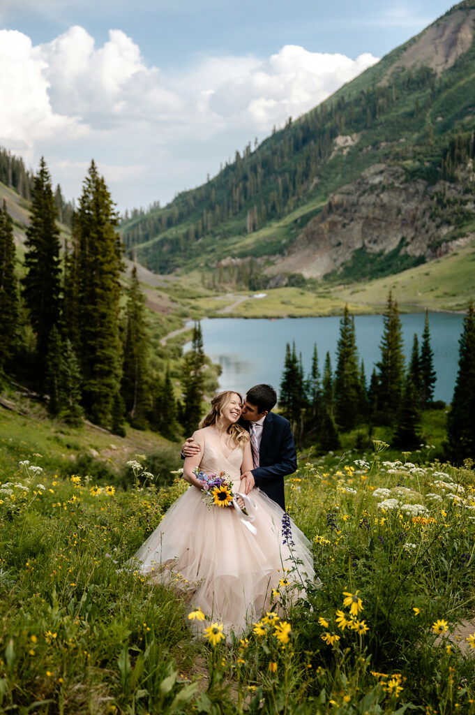 A couple stands in wildflowers smiling. 