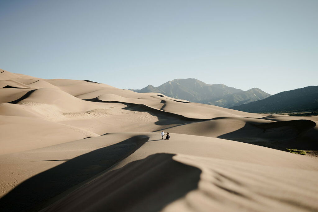 A couple standing in sand dunes.